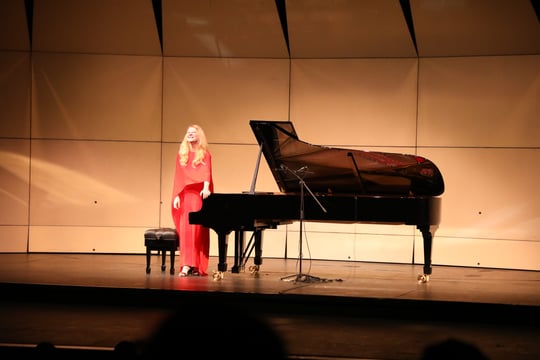 Pianista Valentina Litsisa con un vestido rojo al lado de su piano