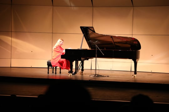 Pianista Valentina Litsisa con un vestido rojo al lado de su piano