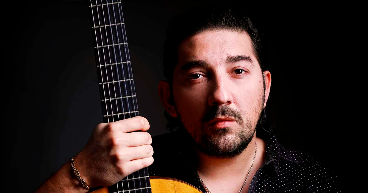 Artista Antonio Rey sosteniendo su guitarra. 