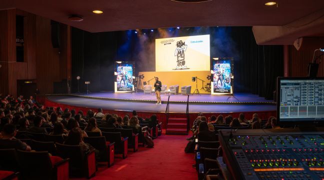 Vista general de un auditorio lleno durante una charla en el escenario.